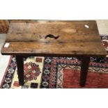An Arts and Crafts style oak stool of rectangular form with shaped cut out to the concave seat,