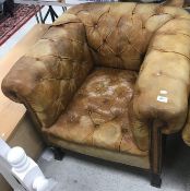 A circa 1900 buttoned leather Chesterfield type armchair on square tapered legs to brass caps and