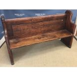 A stained pine chapel pew of plain form on chamfered plank end supports,
