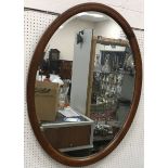 An oval walnut framed wall mirror with bevel edged plate, 89.