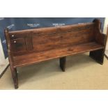 A stained pine chapel pew of plain form on chamfered plank end supports,