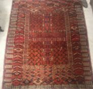 A Hatchli Bokhara rug, the central panel set with black design on a red ground within a stepped red,