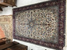 A Kashan carpet, the central panel set with floral and hook motif decorated medallion on a cream