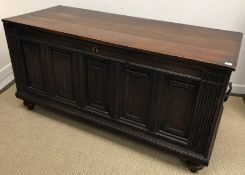 A 17th Century and later oak coffer, the replacement top over a five panel front, flanked by