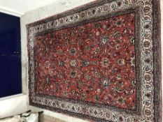 A Persian carpet, the central panel set with all over floral and foliate decoration on a red