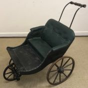 A 20th Century faux leather buttoned child's pram/pushalong buggy with wooden footboard and iron and