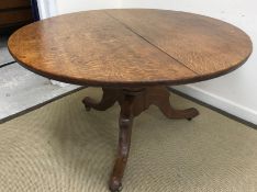 A Victorian oak breakfast table, the circular snap top on a turned and ringed pedestal to hipped