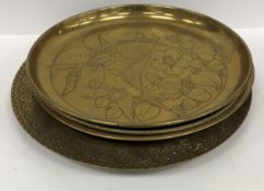 A collection of four brass trays, one in