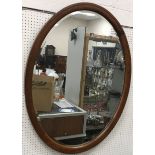 An oval walnut framed wall mirror with b