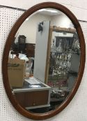 An oval walnut framed wall mirror with b