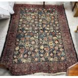 A Persian rug, the central panel set with all-over floral decoration on a dark blue ground,