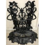 A painted cast iron umbrella stand of two maidens holding flowering cornucopias,