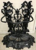 A painted cast iron umbrella stand of two maidens holding flowering cornucopias,