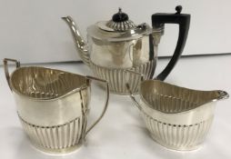 A late Victorian silver three-piece tea set with half-reeded decoration,