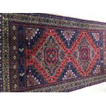 A Persian rug, the central panel set with two repeating medallions,