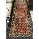 A vintage Caucasian runner, the central panel set with repeating hook motifs on a red ground,