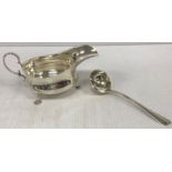 A George V silver sauceboat with scrolling handle, raised on three hoof feet (by Martin Hall & Co.
