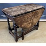 An 18th Century oak oval gate-leg drop-leaf dining table on baluster turned and ringed supports
