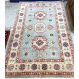 An Afghan Kazak rug, the central panel set with square and lozenge medallions on a pale blue ground,