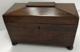 A Victorian rosewood sarcophagus shaped tea caddy with hinged lid opening to reveal a fitted