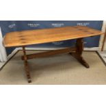 An Ercol elm rounded rectangular dining table on trestle end supports united by a centre stretcher