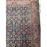 A Persian rug, the central panel set with all-over floral decoration on a dark blue ground,