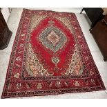 A Persian rug, the central panel set with floral decorated medallion on a red,