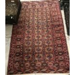 A Tekke Bokhara rug, the central panel with elephant foot medallions on a rust coloured ground,