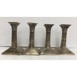 A pair of George V silver squat table candlesticks of stop fluted Corinthian column form on stepped