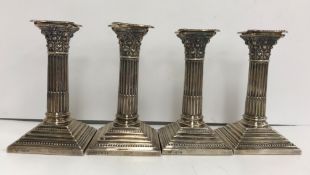 A pair of George V silver squat table candlesticks of stop fluted Corinthian column form on stepped