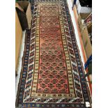 A vintage Caucasian runner, the central panel set with repeating hook motifs on a red ground,