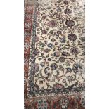 An old Persian carpet, the central panel set with scrolling foliate decoration on a mushroom ground,