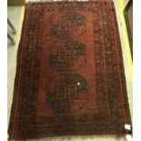 A Bokhara rug, the central panel set with three medallions on a dark red ground,