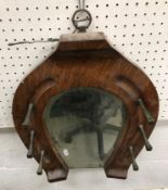 An early 20th Century oak horseshoe shaped hall mirror with brass square cut nail hooks 38 cm wide