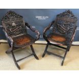 A pair of circa 1900 Japanese carved hardwood folding chairs with dragon carved top rail and