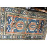 A Caucasian rug, the central panel set with two repeating medallions on a terracotta ground,