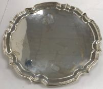 A modern silver salver in the Georgian style, with pie-crust rim, raised on three scroll feet (by J.