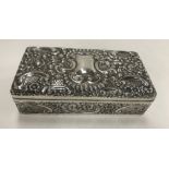 An Edwardian embossed silver rectangular cigarette box with all-over scrolling foliate and floral