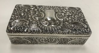 An Edwardian embossed silver rectangular cigarette box with all-over scrolling foliate and floral