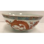 A Chinese porcelain bowl decorated in oxide red and gilt highlighting with five toed dragons