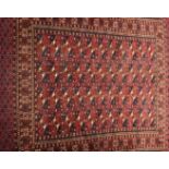 A Bokhara rug, the central panel set with repeating medallions on a red ground,