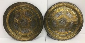 A pair of Middle Eastern brass white metal and copper inlaid chargers with script and foliate