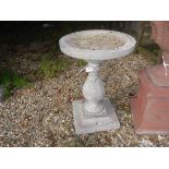A composite stone bird bath of simple baluster form on a stepped square base 64 cm high