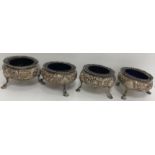 A set of four Victorian embossed silver open salts of floral decorated cauldron form,