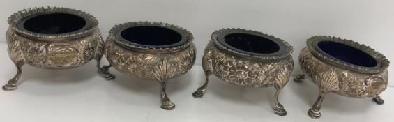 A set of four Victorian embossed silver open salts of floral decorated cauldron form,