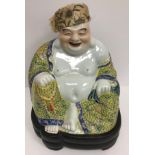 A Chinese porcelain figure of a seating smiling Buddha in a yellow ground famille rose gown bearing