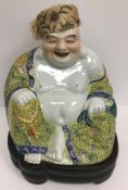 A Chinese porcelain figure of a seating smiling Buddha in a yellow ground famille rose gown bearing