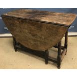 A 19th Century oak oval gate-leg drop-leaf dining table on turned supports united by stretchers,