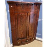 A 19th Century mahogany bow fronted hanging corner cupboard with two arched panelled doors