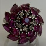 An 18 carat white gold flower head cluster ring set with ten navette cut rubies,